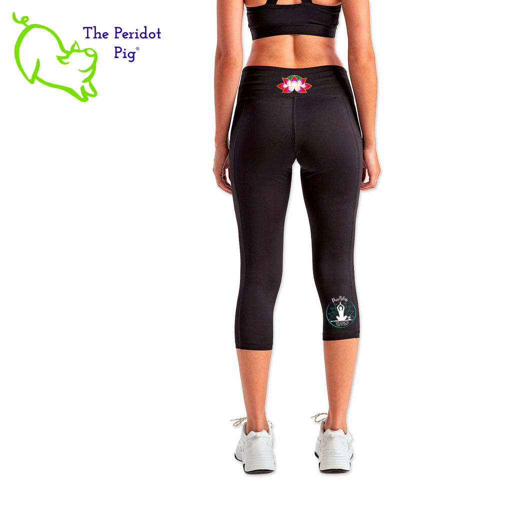 Luxuriate in luxury with the PureBliss Studios Lotus High Rise Capri Legging—super comfortable and breathable with two side pockets, an interior pocket, plus the brand logo on the back right leg in a matte vinyl and a dazzling color lotus on the back. And who wouldn't love a little "love" on the left pocket? Stretchy yet snug-fitting, enjoy the perfect yoga session! Back view shown.