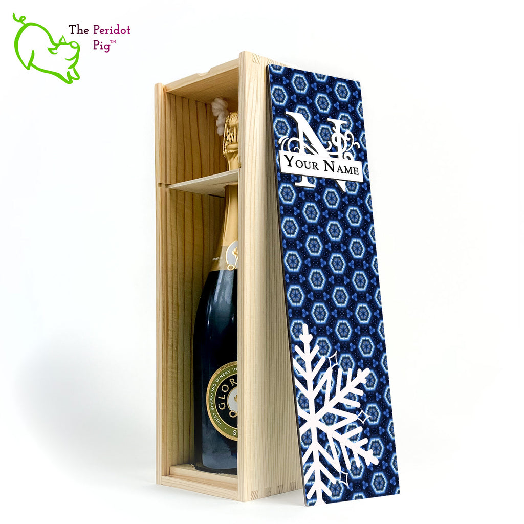 The wine box front panel is decorated in a glossy, detailed print with a white monogram and space for a customized name. This model has a deep blue background with crystalized pattern. In the foreground is a large white snowflake. Shown in natural with an interior view of a sample wine bottle.