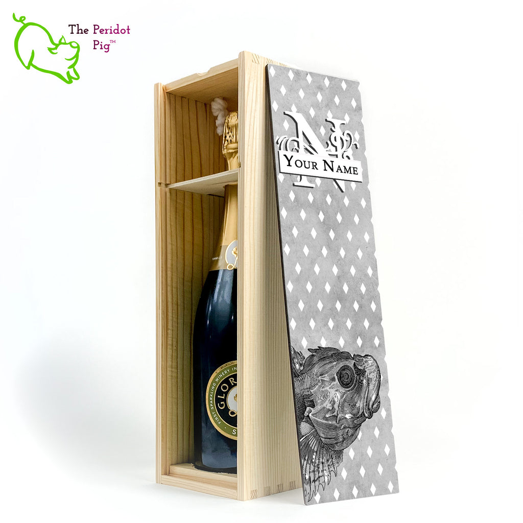 The wine box front panel is decorated in a glossy, detailed print with a white monogram and space for a customized name. This model has a smokey gray background with a pattern of white diamond shapes. In the foreground is a large black line drawing of a fish. Natural finish showing the interior and a sample wine bottle.