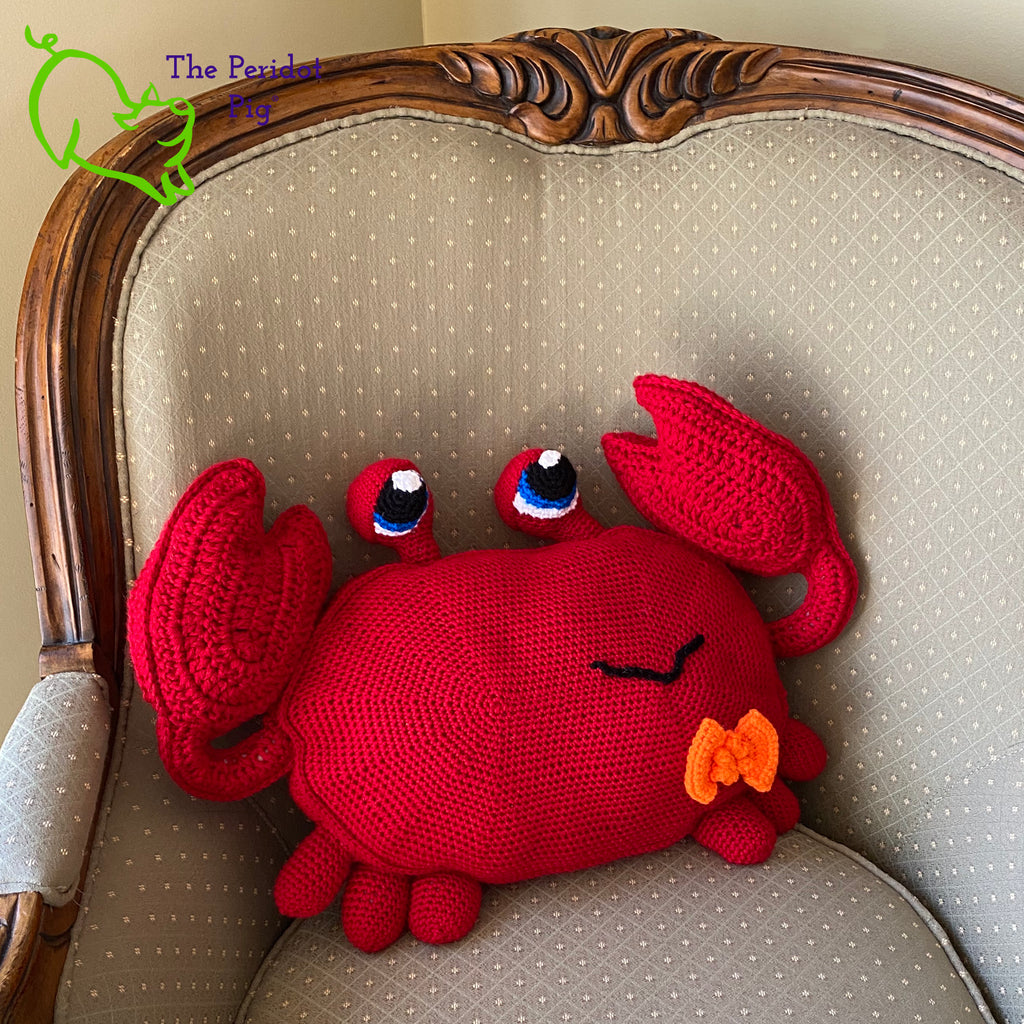 Clarke is a really large amigurumi pillow! Some think he can be a bit terse but he's really the life of the party. Those eyes pop up and just seem to say, "Hellloooooo!" He's dressed for the occasion with his spiffy little bow tie. Front view shown in a chair.