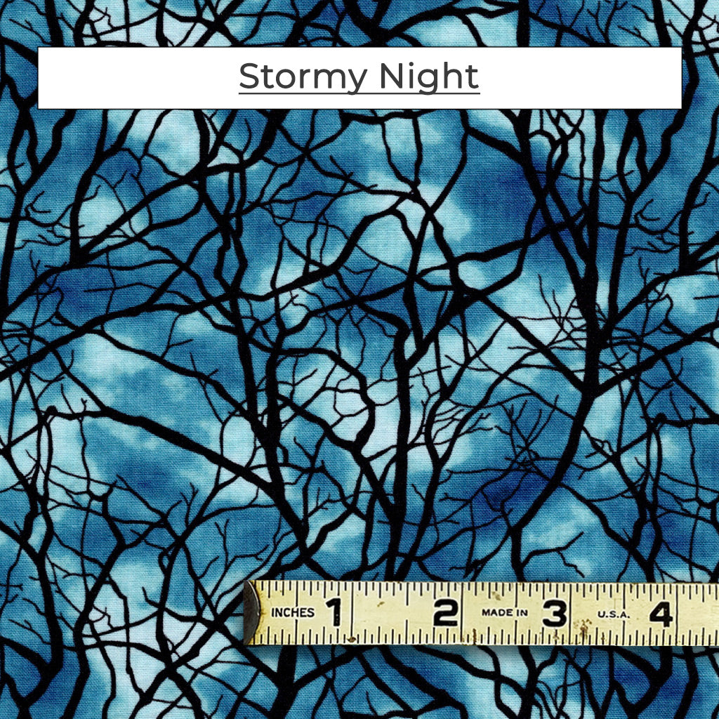 A creepy pattern of tree branches with a mottled blue, stormy sky in the background. The Stormy Night fabric glows in the dark too!