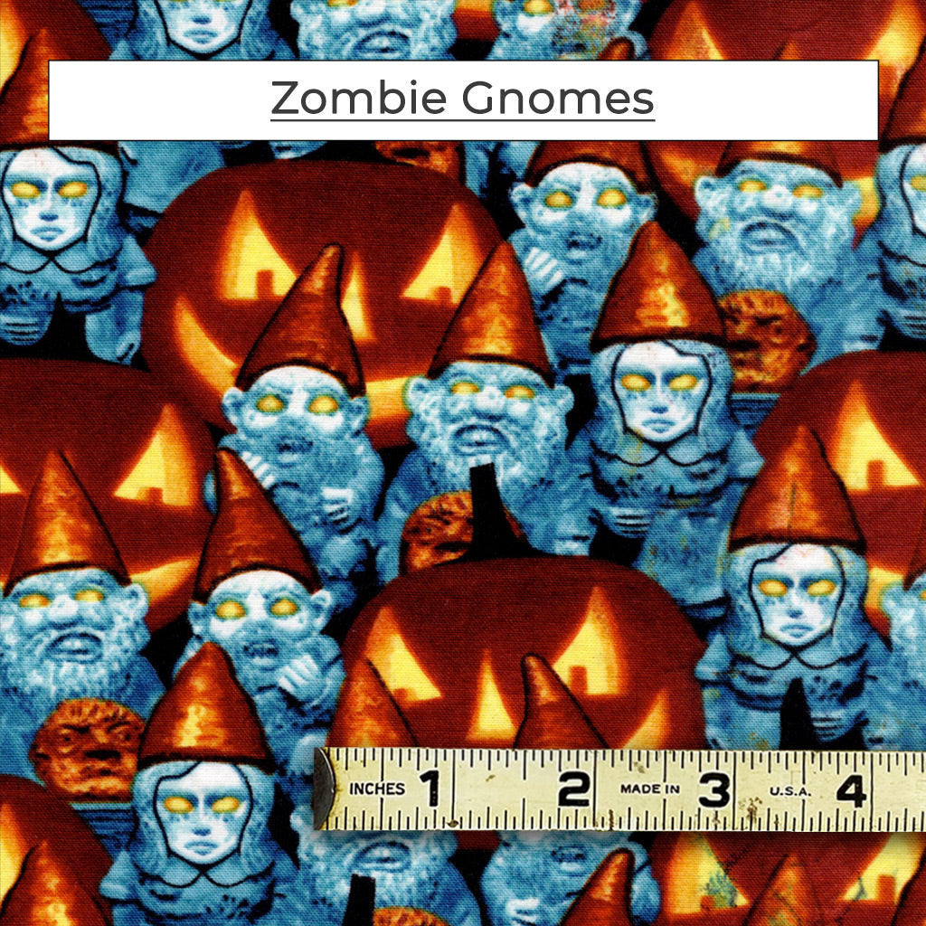 Blue toned zombie garden gnomes with glowing yellow eyes amid jack-o-lanterns.  The Zombie Gnomes fabric glows in the dark too!