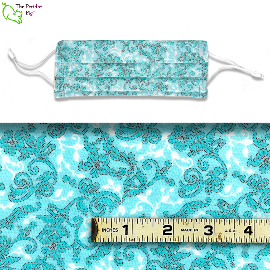 Delicate scrolling vines with flowers set on a light blue and white background. This fabric makes us want to shop at Tiffany's! Called Blue Floral. View of the mask and fabric scale.