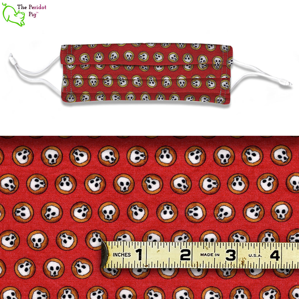 A mixed color fabric with a red background and tiny little skulls in dark gold circles called Steampunk Skulls. A view of the mask and the fabric scale.