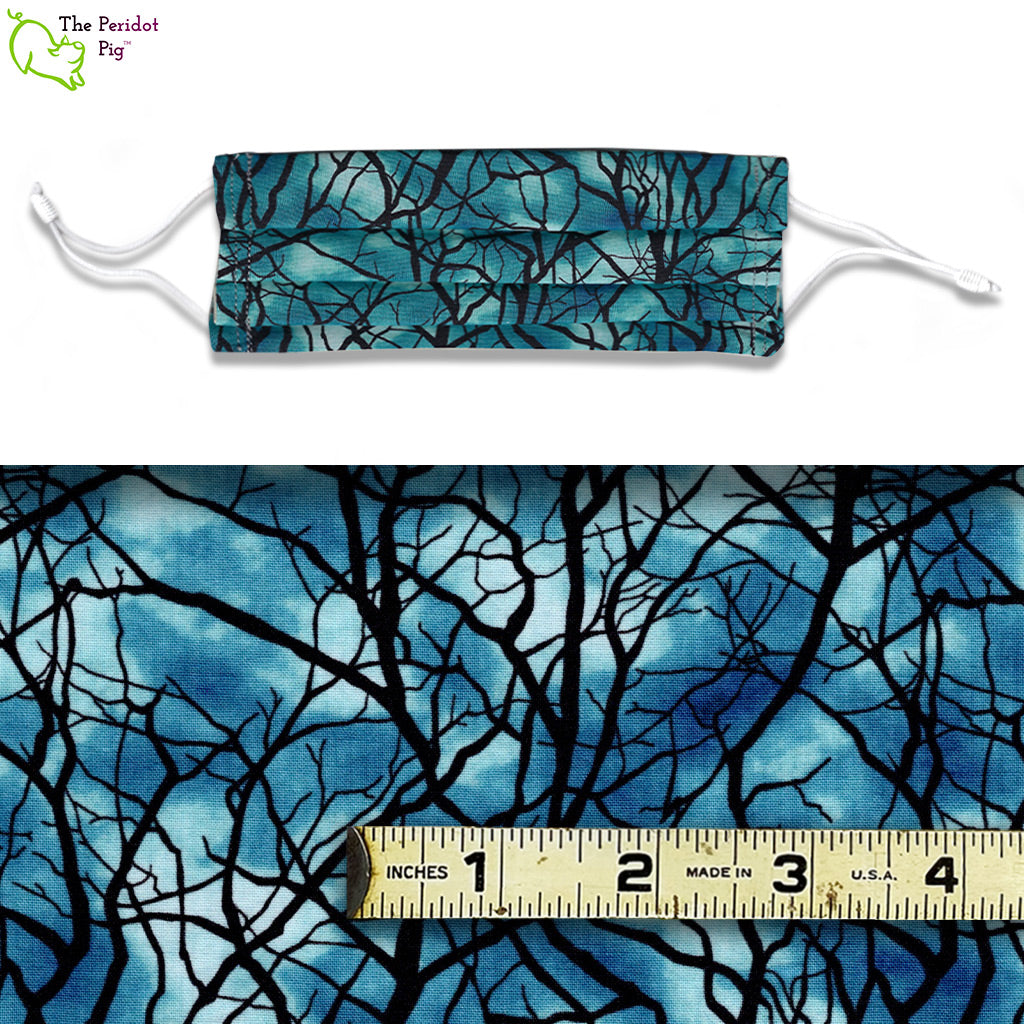 A view showing the mask and the scale of the pattern. A creepy pattern of tree branches with a mottled blue, stormy sky in the background. The Stormy Night fabric glows in the dark too!